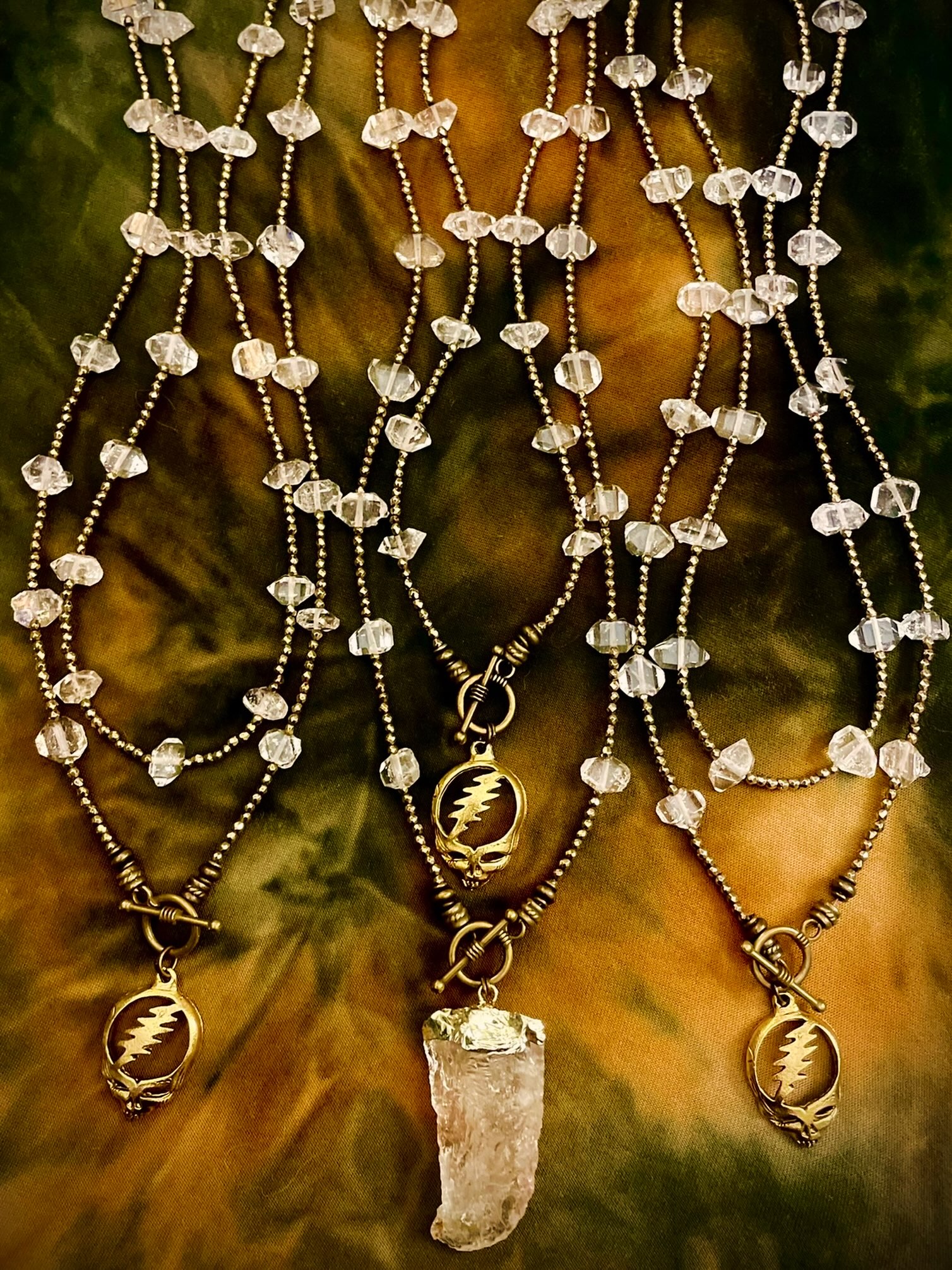Herkimer diamond necklaces arranged on warm gold fabric